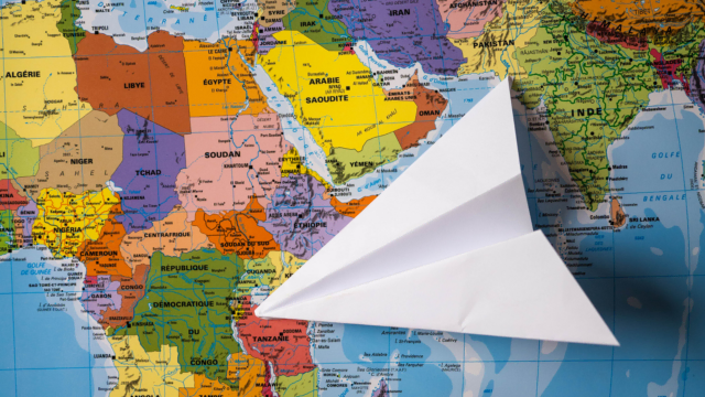 Un avion en papier est posé sur un planisphère au niveau de l'Afrique.