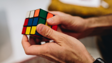 Deux mains manipulent un rubix cube.