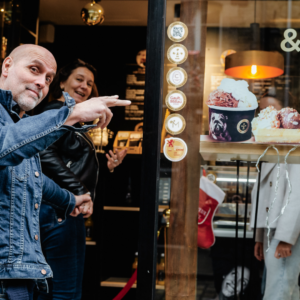 Deux personnes entrent joyeusement dans une boutique Moustache Artisan Glacier.