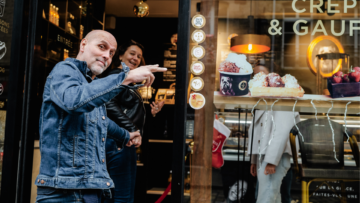 Deux personnes entrent joyeusement dans une boutique Moustache Artisan Glacier.