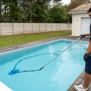 Salarié Quality Piscine entrain de nettoyer une piscine