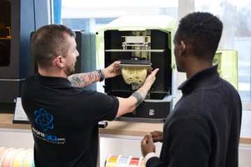 2 personnes discutant devant une machine à impression 3D