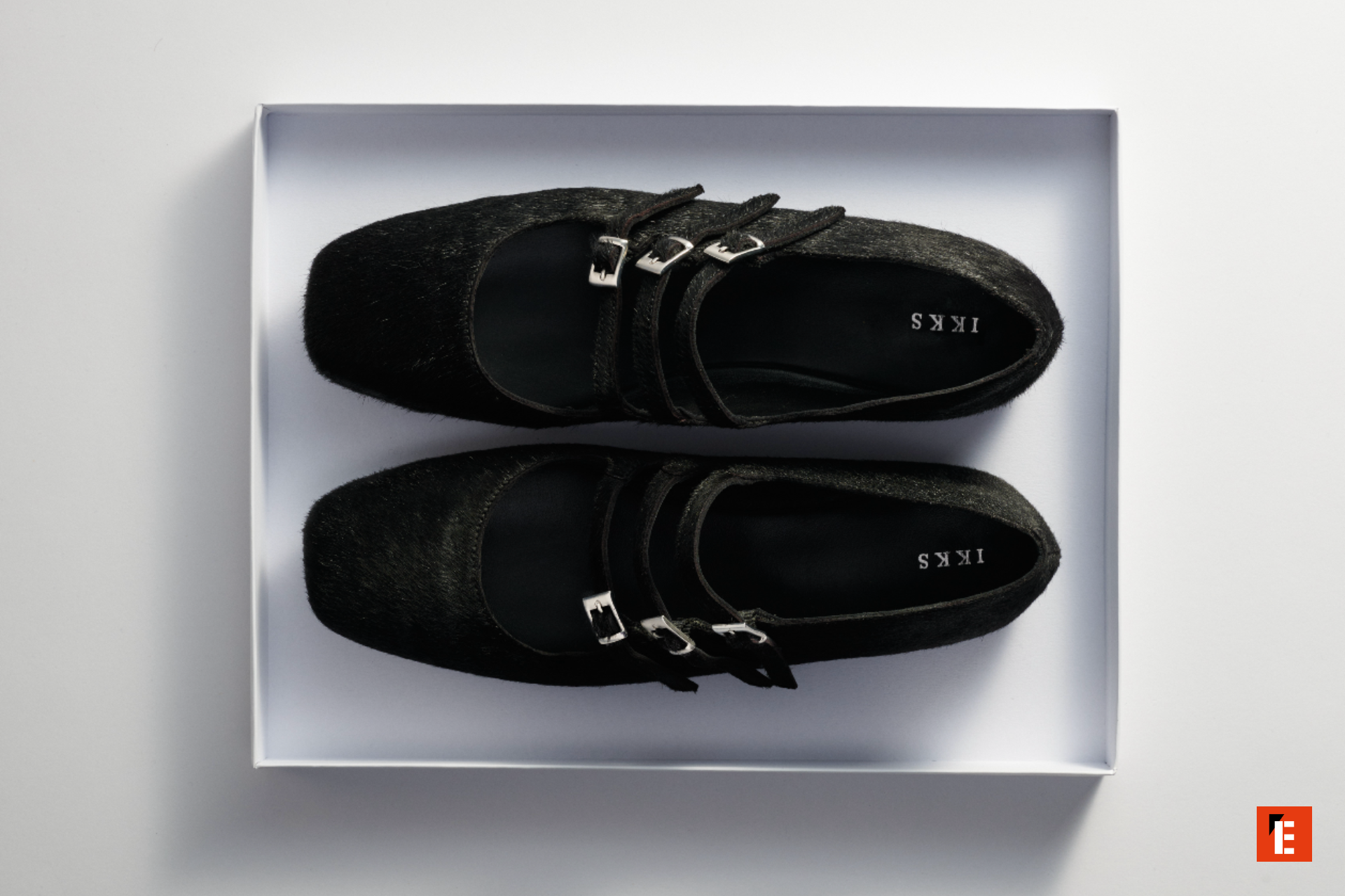 Chaussures noires avec boucles, présentées dans une boîte.