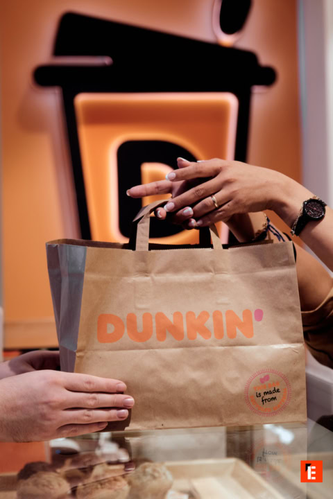Un sac de Dunkin' avec des mains qui le tendent.
