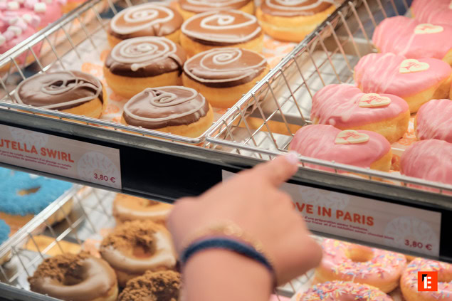 Variété de donuts en vitrine, main pointant