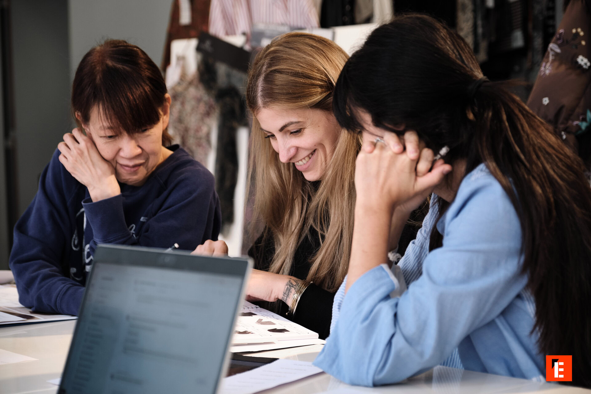 Trois femmes discutent autour d'une table de travail.