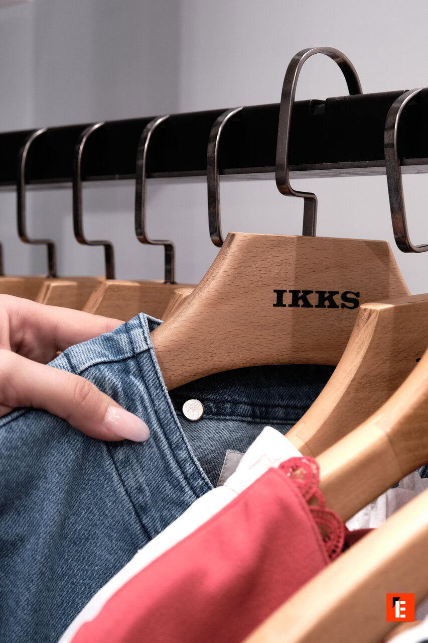 Main tenant un vêtement sur un porte-manteau.