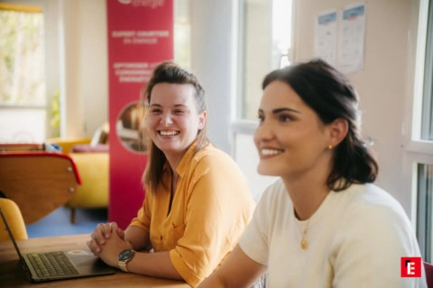 Deux femmes souriantes dans un environnement de travail.