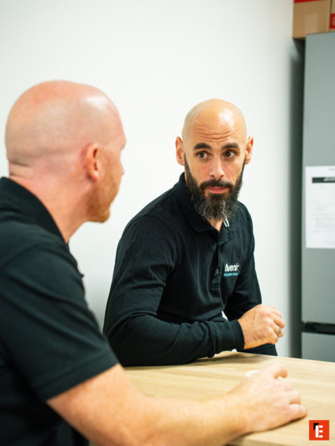 Dos hombres conversando en una oficina moderna.