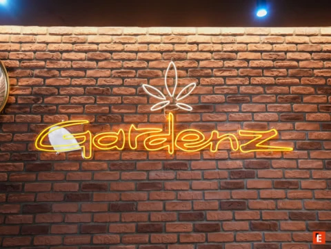 Logo lumineux GardenZ sur mur en briques.