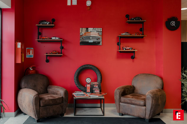 deux fauteuils posé devant un mur rouge avec des étagères