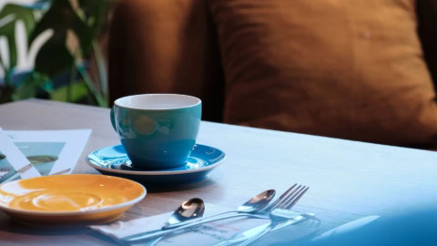 Une tasse de thé ou de café bleue sur une table de restaurant.