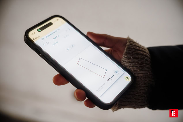 Personne tenant un smartphone avec une mesure visible.