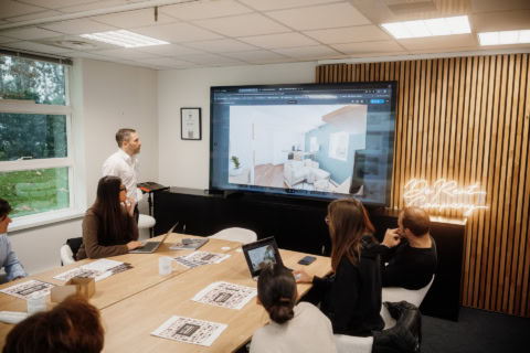 Equipe en salle de réunion autour d'une table devant un diapo