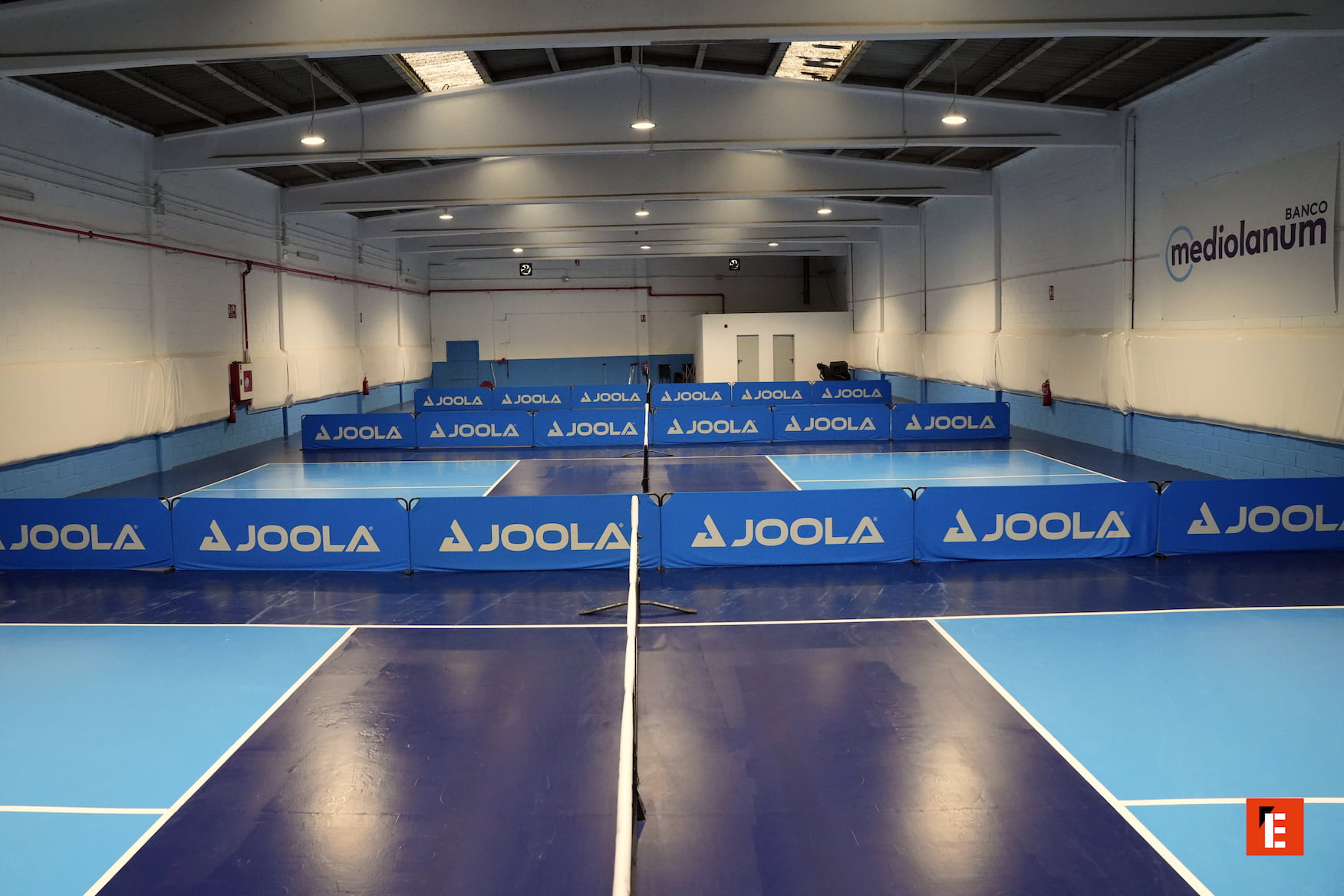 Sala de tenis de mesa con mesas y redes.