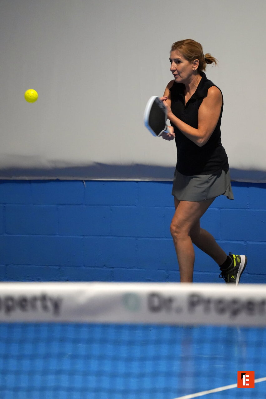 Mujer jugando al tenis en pista cubierta