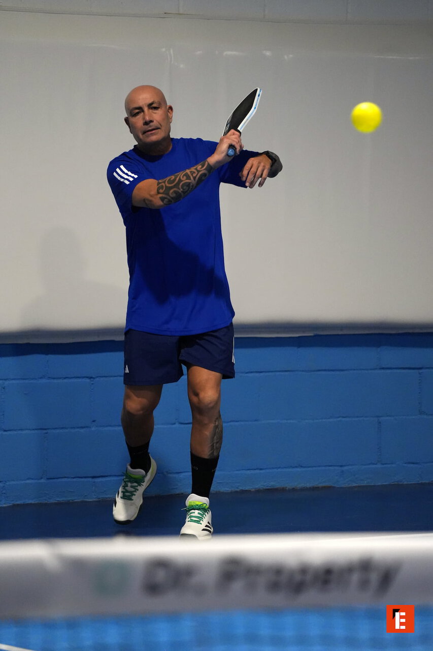Jugador de pádel golpeando una pelota amarilla.