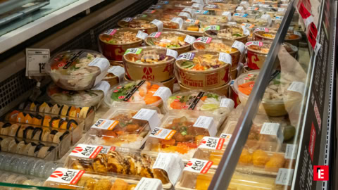 Femme souriante en veste orange dans un magasin.