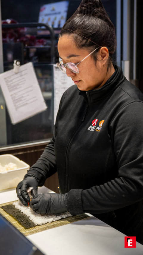 Cinq sushis colorés sur une assiette noire.
