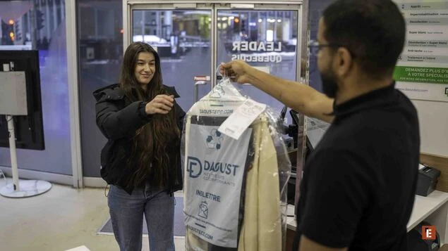 Femme récupérant un vêtement au comptoir.