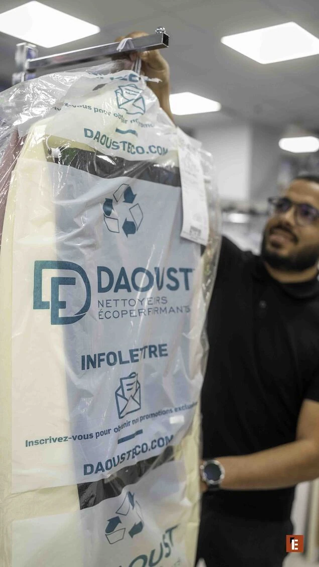 Homme tenant un vêtement dans un sac transparent.