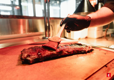 Un chef badigeonne une côtelette de barbecue.