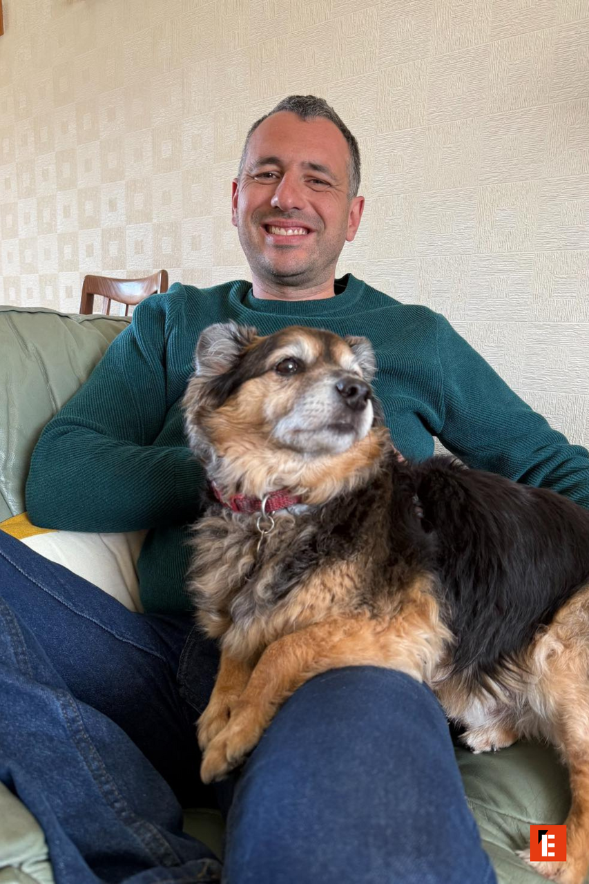 Man smiling with a dog on his lap.