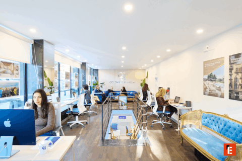 Hombre sonriente frente al logo de Coldwell Banker.