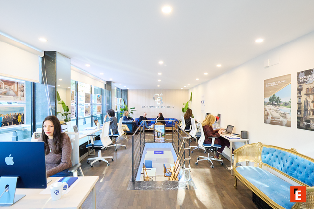 Hombre sonriente frente al logo de Coldwell Banker.