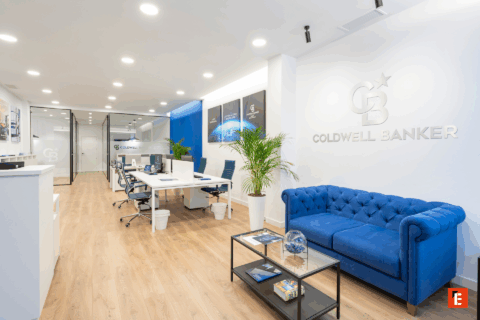 Oficina moderna de Coldwell Banker con mobiliario claro.