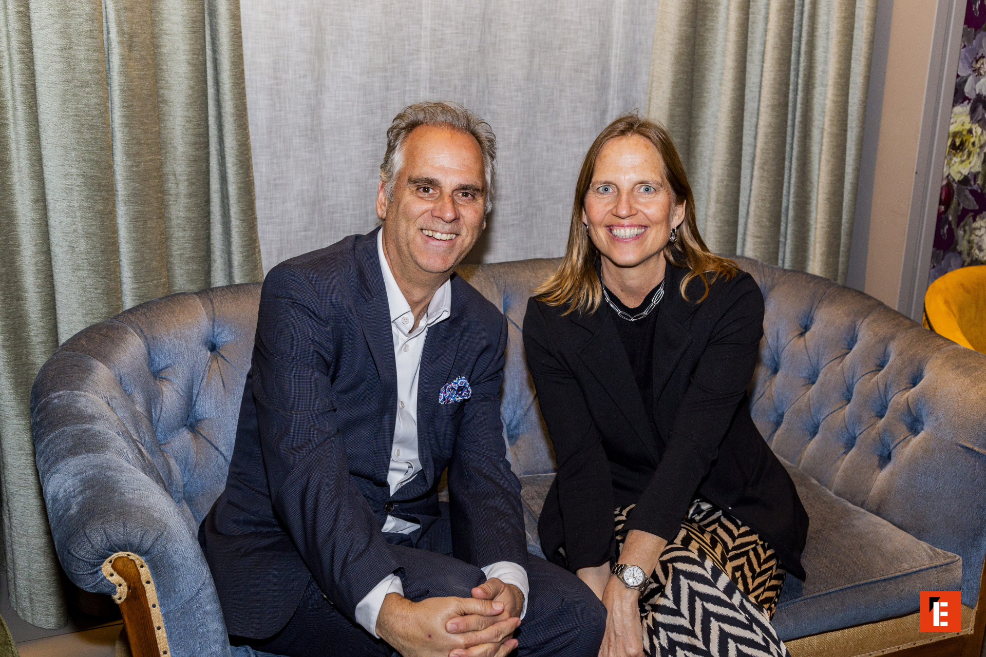 Pareja sonriente sentada en un sofá elegante.