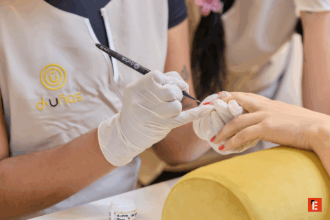 Manicura profesional con esmalte rosa y herramientas.