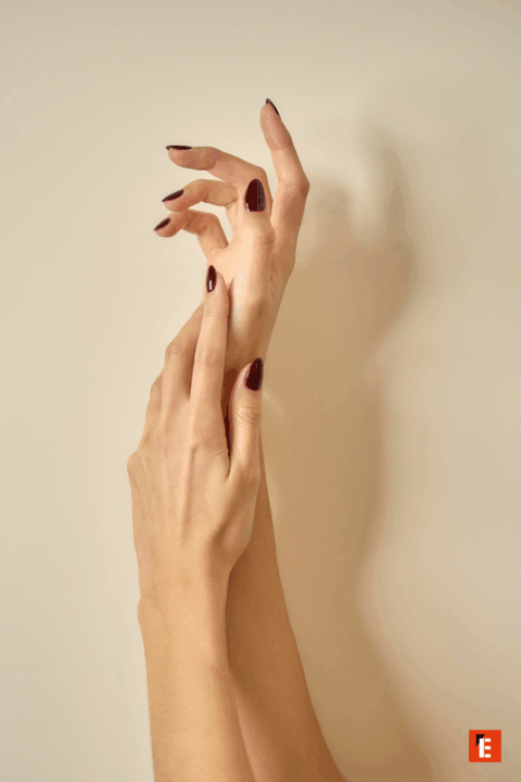 Manos elegantes con esmalte de uñas oscuro.