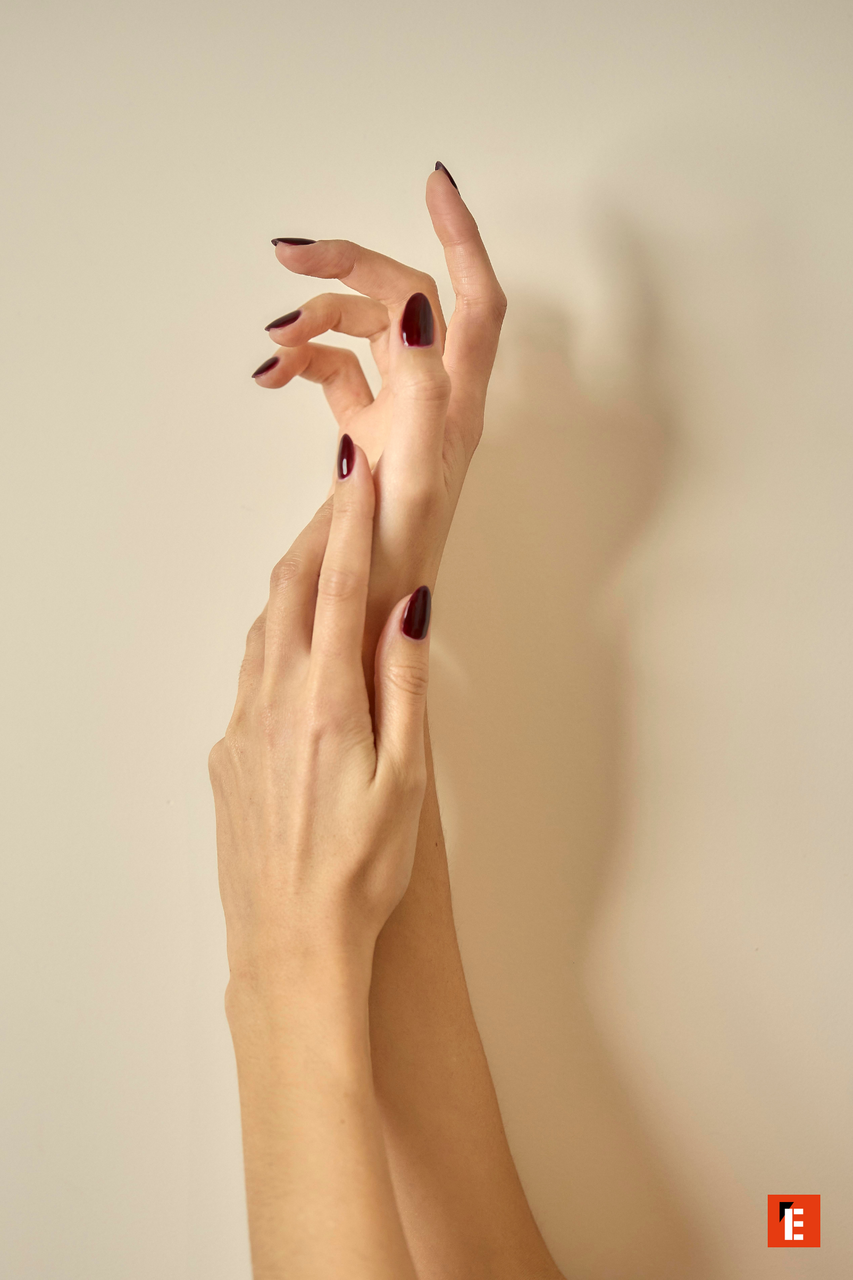 Manos elegantes con esmalte de uñas oscuro.