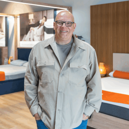 Man smiling in a bedding showroom.