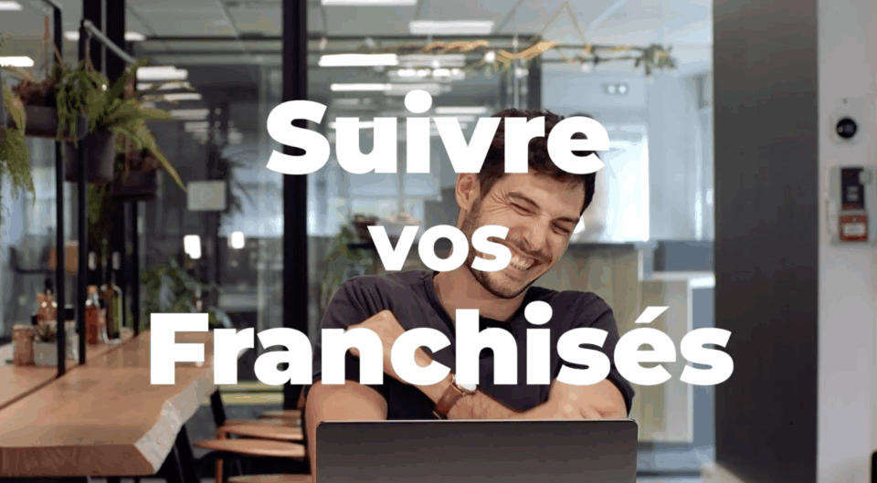 Un homme souriant devant un ordinateur portable.