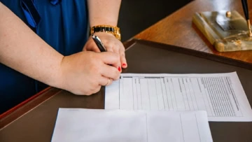 Mano scrivendo su un documento su un tavolo