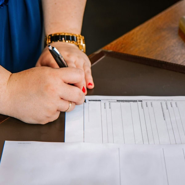 Mano scrivendo su un documento su un tavolo