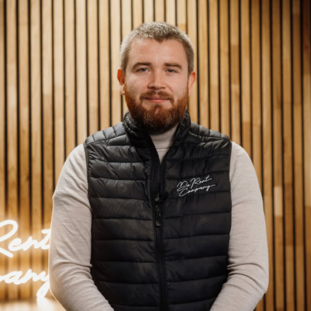 Homme souriant devant un mur en bois.