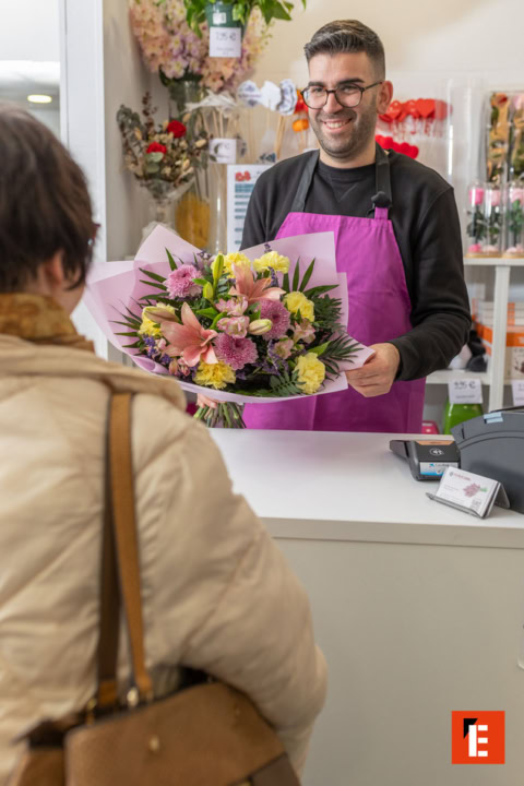florista entrega ramo a cliente en floristería