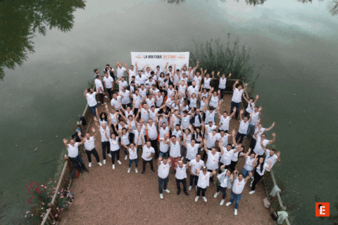 Groupe souriant levant les bras au bord de l'eau.