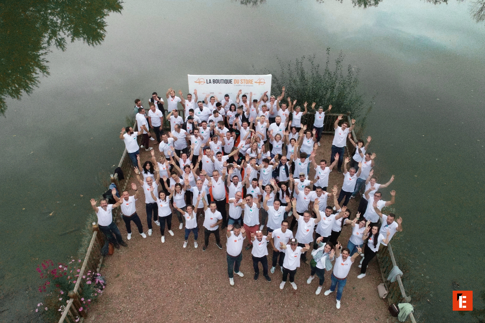 Groupe souriant levant les bras au bord de l'eau.