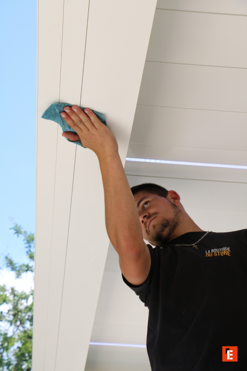 Un homme nettoie un plafond en bois blanc.