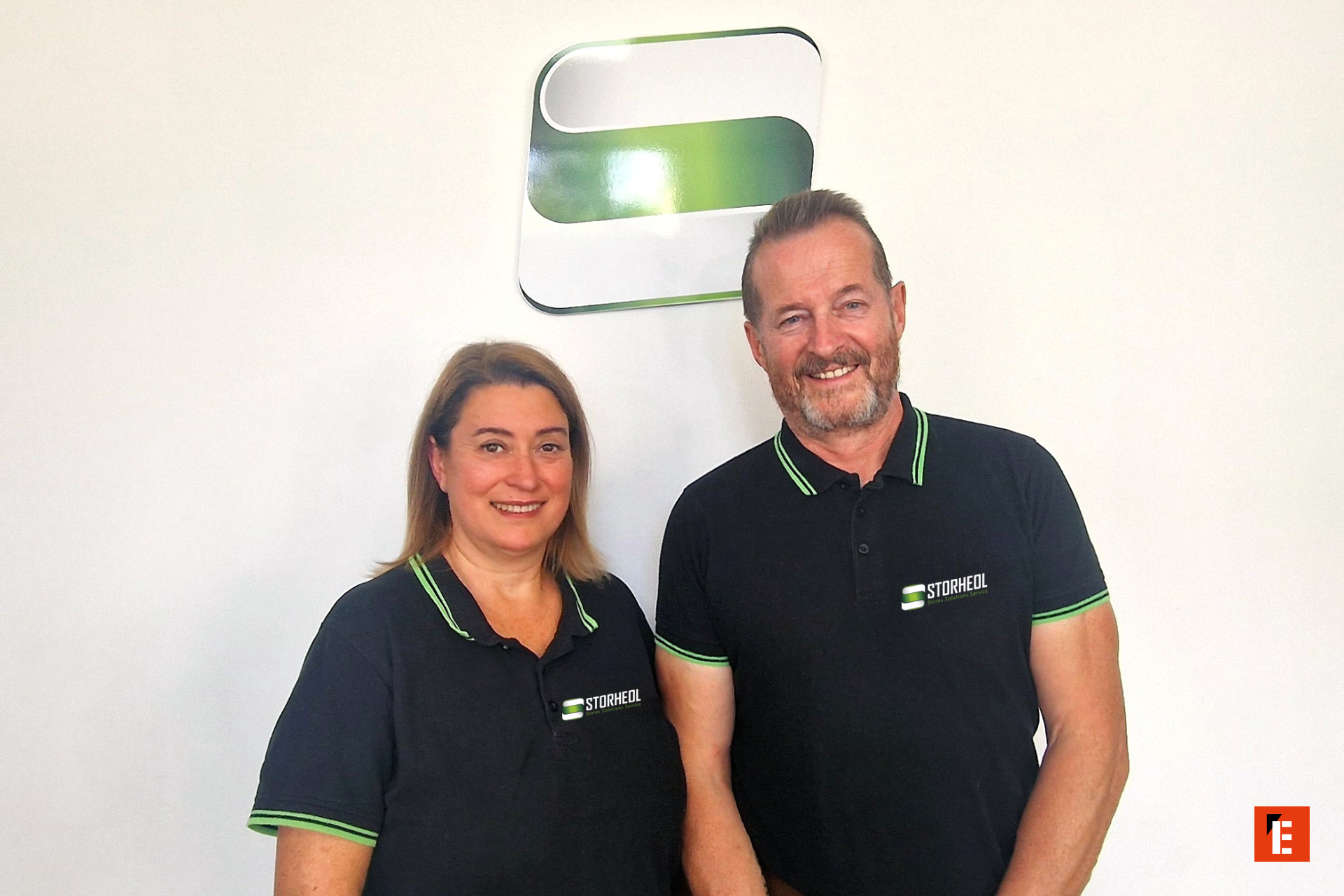 Deux personnes souriantes en t-shirts noirs avec logo.