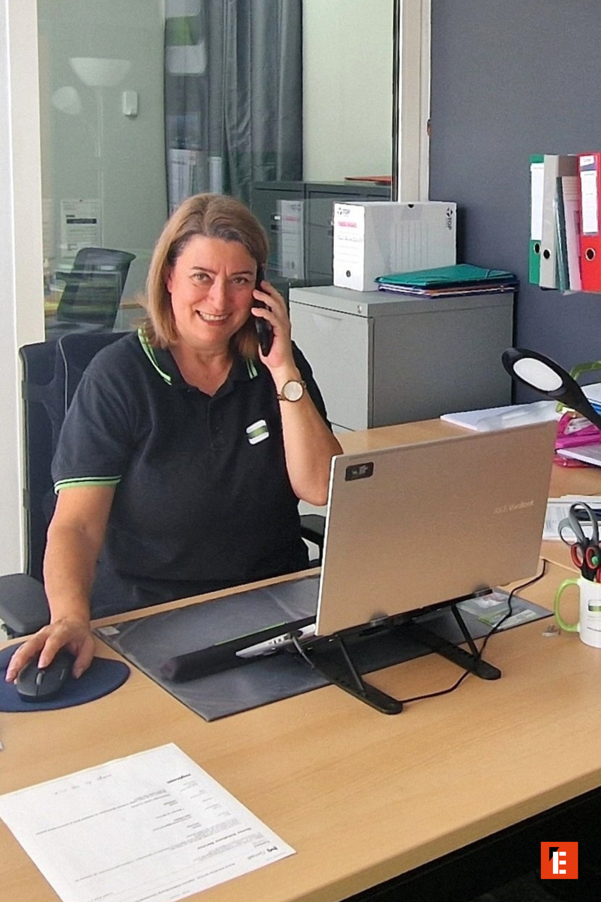 Femme au bureau souriante au téléphone.