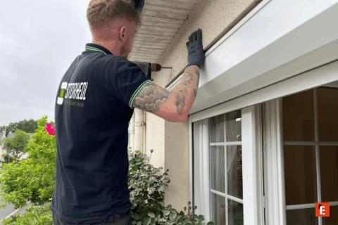 Technicien installant un auvent sur une fenêtre.