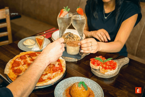 deux personnes trinquant avec des plats italiens