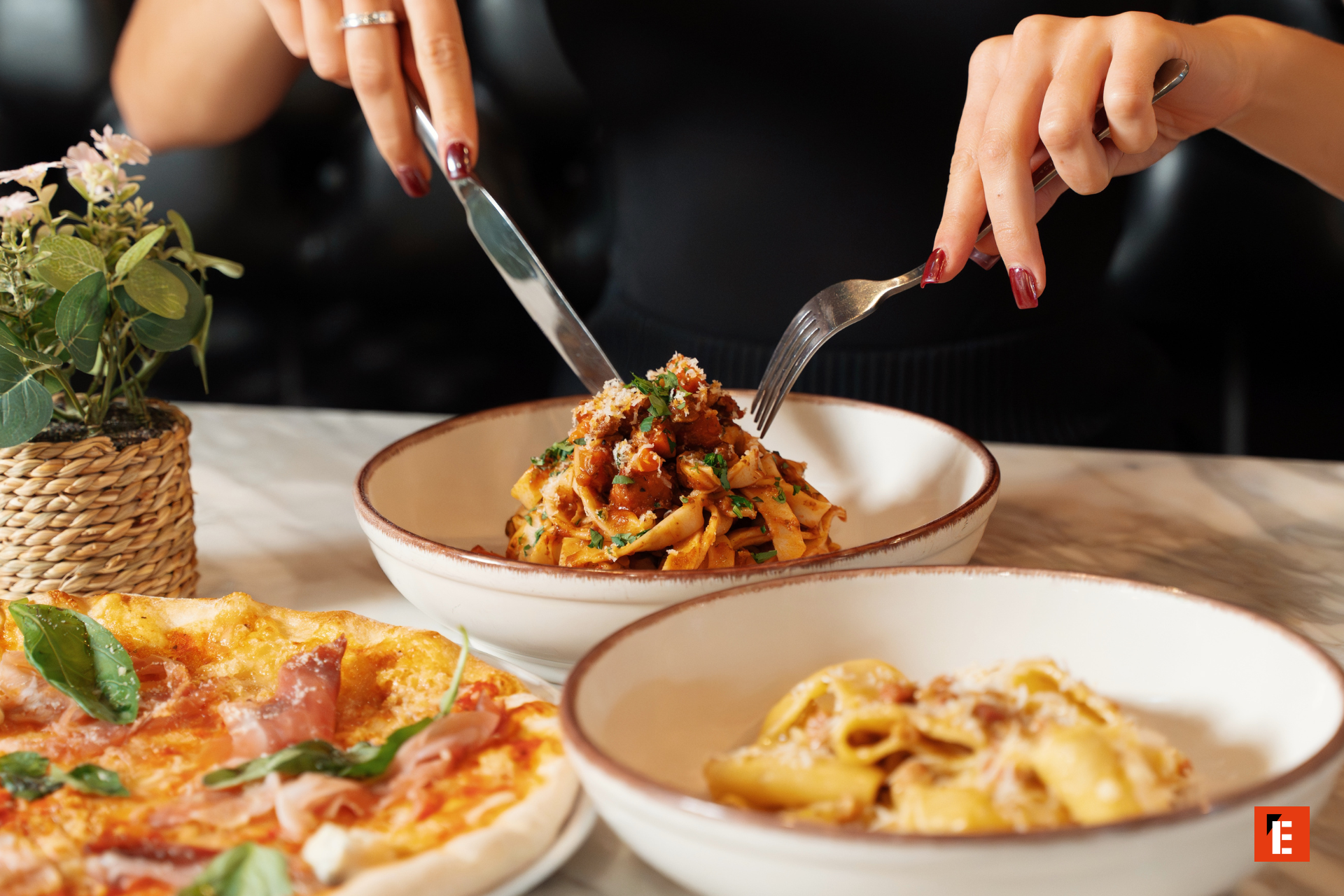 personne coupant un plat de pâtes bolognaise