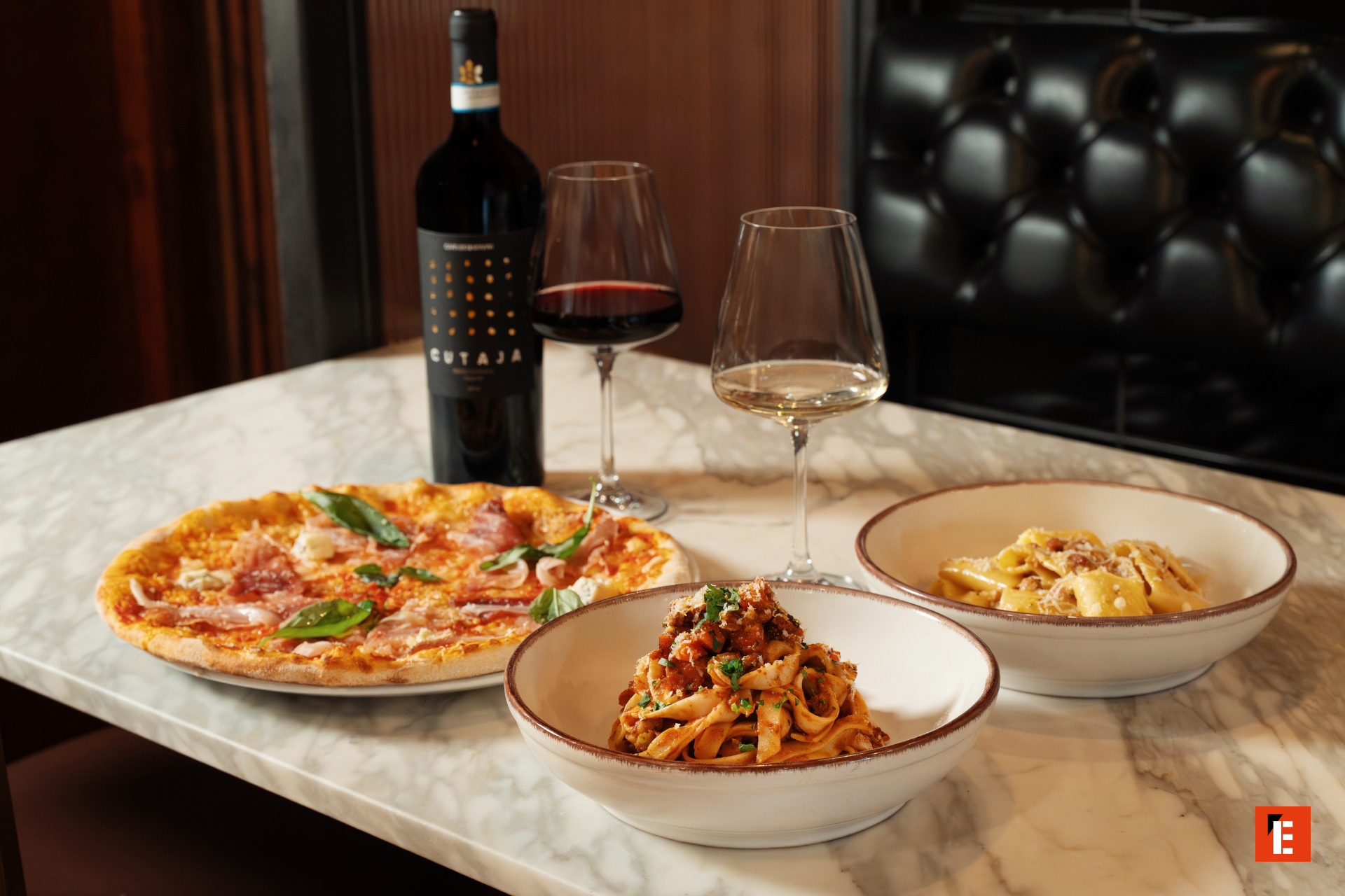 plats italiens posés sur une table avec une bouteille de vin rouge