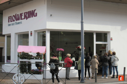 Tienda de flores con clientes en fila.